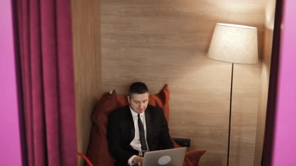 Hombre maduro cansado trabajando en el ordenador portátil sentado en la silla de la bolsa de frijol en la oficina . — Vídeo de stock