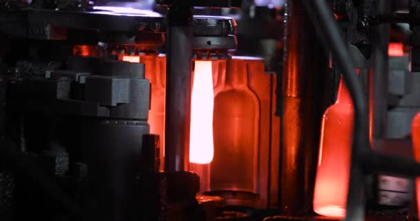 Automated process of forming bottle of molten glass on conveyor line, closeup. — 비디오