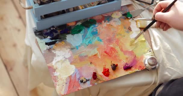 Professional paintress mixing oil paints on palette using brush, hand closeup. — 비디오