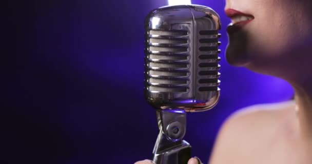 Mavi arka planda mikrofonda şarkı söyleyen kadın şarkıcı, yakın plan dudak manzarası. — Stok video