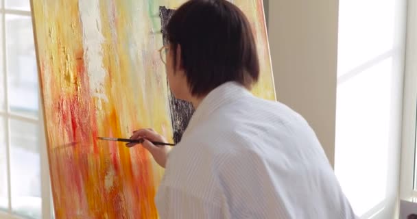 Woman paintress painting multicolor picture using brush on canvas on easel. — 비디오