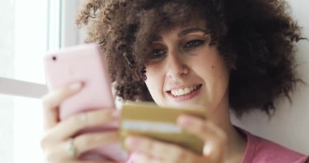 Retrato de la mujer feliz está haciendo pago en línea con tarjeta bancaria usando el teléfono inteligente . — Vídeos de Stock