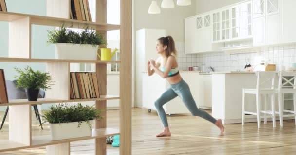 Deportiva mujer joven haciendo ejercicio de sentadilla en la sala de estar, vista lateral . — Vídeo de stock