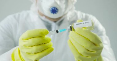 Doktorlar şırıngayı koronavirüs aşısıyla doldurup enjeksiyona hazırlanıyorlar..
