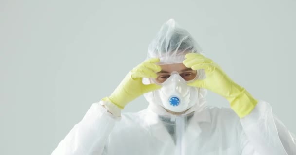 Docteur en combinaison de protection enlève respirateur et lunettes, en regardant la caméra . — Video