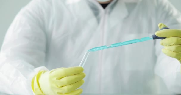 Doctor gotea solución azul en tubo de vidrio, pandemia de coronavirus, primer plano de las manos . — Vídeo de stock
