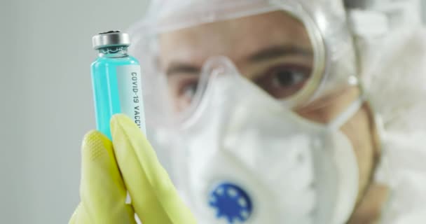 Doctor holding covid-19 coronavirus vaccine and looking on it, portrait closeup. — Stock video