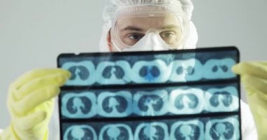 Koruyucu giysili doktor beyin tomografisi öğreniyor. Covid-19 'daki röntgen görüntüsünü tara..