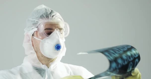 Портрет врача в защитной одежде, глядя на снимок КТ мозга, covid-19 . — стоковое видео