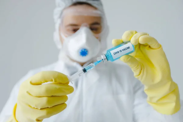 Retrato del médico en ropa protectora llena jeringa con vacuna contra el coronavirus . — Foto de Stock