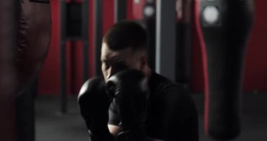 Saldırgan boksör eldivenli genç adam boks yapıyor ve spor salonunda kameraya bakıyor..