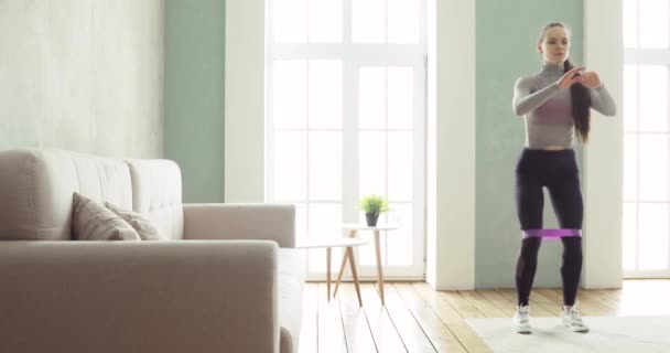 Woman is training making squats exercises at home in living room, front view. — Stock Video