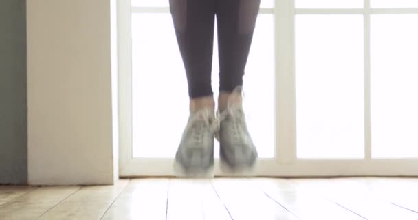 Pernas de mulher esportiva está pulando corda fazendo treinamento cardio em casa na cozinha . — Vídeo de Stock