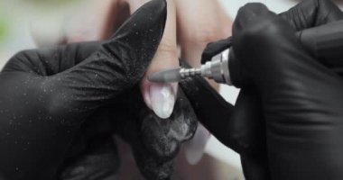 Manikür ustası elektrikli makine kullanarak kadın tırnağından eski Shellac 'ı söküyor..