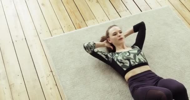 Atletisk ung kvinna gör magövningar crunches på golvet hemma, ovanifrån. — Stockvideo