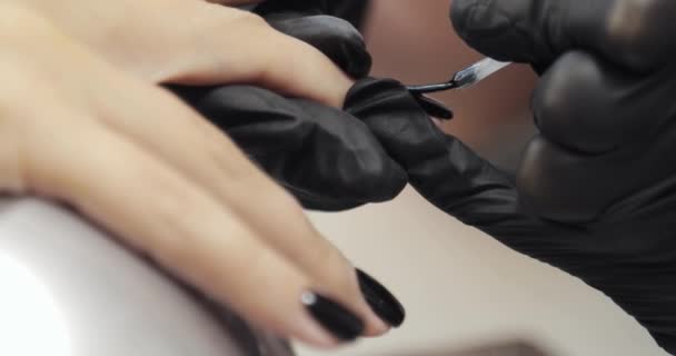 Donna su manicure con gommalacca nera in salone di bellezza, primo piano mani . — Video Stock