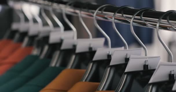 Rij van mannen pak jassen op hangers. Verzameling van nieuwe mooie kleren opknoping op hangers in een winkel. — Stockvideo