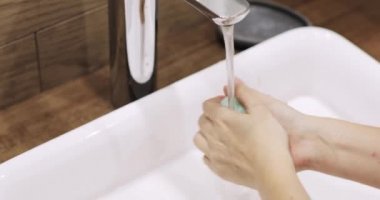 Kadın ellerini en iyi şekilde yıkıyor. Coronavirüs suyu duruluyor. Suyu ovuyor, havluyu kurutuyor.
