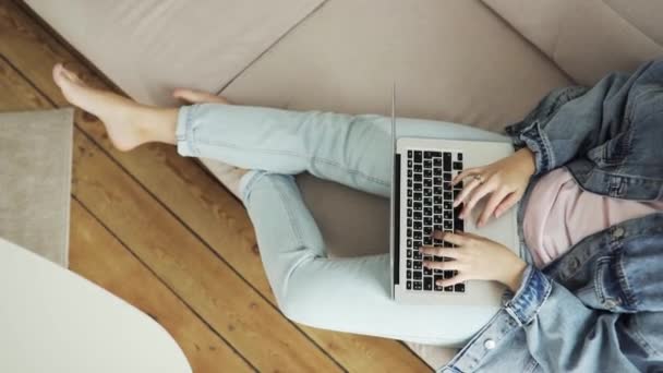 Vista dall'alto delle mani delle donne che lavorano scrivendo digitando sul computer portatile seduto sul divano . — Video Stock