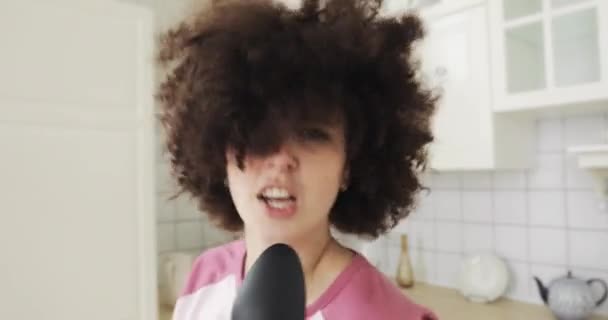 Portrait of girl singing in kitchen using spoon as microphone looking at camera. — Stock Video