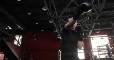 Boksör boks eldivenli genç adam spor salonunda kameraya bakıyor..