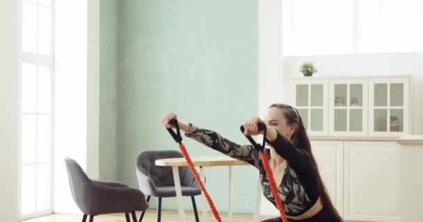 Mulher desportiva está fazendo agachamentos com expansor de esporte ter treinamento de fitness . — Vídeo de Stock