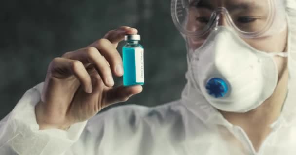 Asian Doctor holding covid-19 coronavirus vaccine, looking on it — стокове відео