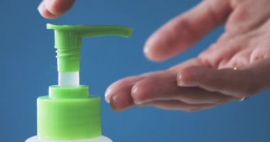 Adam dezenfektanla ellerini temizlemek için şişeye bastırıyor..