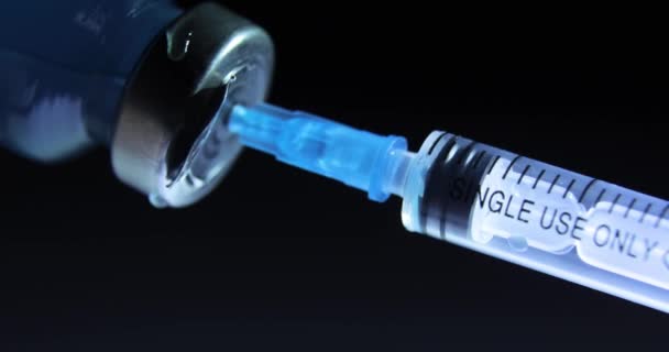 Dials blue coronavirus vaccine into syringe on black background, COVID-19. — Stock Video