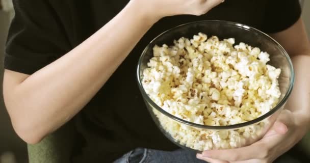 Jonge vrouw eten verse popcorn uit glas transparante kom, handen closeup. — Stockvideo