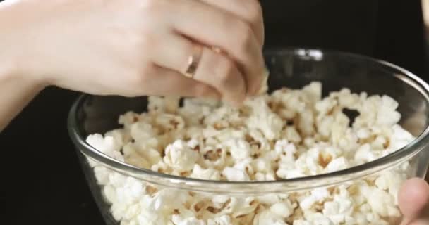 Close-up-Schüssel mit Popcorn und Frauenhänden, die Filmfutter nehmen und essen. — Stockvideo