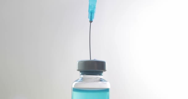 Dials blue coronavirus vaccine into syringe on light background, closeup view. — Stock Video