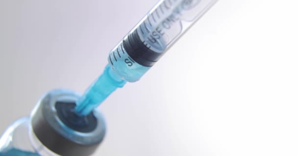 Dials blue coronavirus, sars, flu vaccine into syringe on light background. — Stock video
