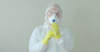 Erkek doktor portresi koruyucu eldivenleri, maskeyi, salgın gözlüğünü çıkarıyor..