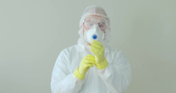 Portret van de man arts doet beschermende handschoenen uit, masker, bril in pandemie. — Stockvideo