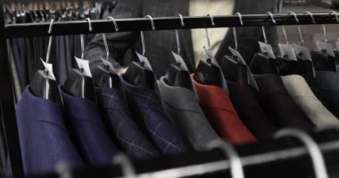 Erkek alışverişi elbise mağazasından takım elbise seçer, eller askıdan yakınlaşır..