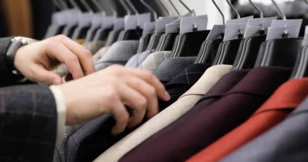 L'uomo sta facendo shopping scegliendo abito da ufficio nel negozio di abbigliamento, mani primo piano . — Video Stock