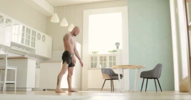 Şortlu atletik adam mutfaktaki amuda kalkma pratiği yapıyor..