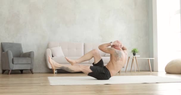 Sporty μυώδης άνθρωπος κάνει κοιλιακούς ασκήσεις crunches στο σπίτι στο πάτωμα, πλευρική άποψη. — Αρχείο Βίντεο