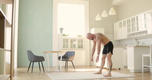 Hombre deportivo en pantalones cortos está practicando handstand en la cocina en casa, vista lateral . — Vídeo de stock