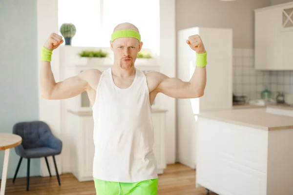 Homme chauve drôle dans la cuisine en vêtements de sport montrant les muscles. style rétro — Photo