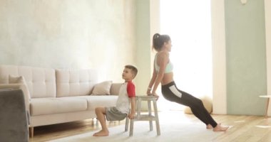 Anne ve oğul birlikte antrenman yapıyorlar. Evde, yan gözle el trisepsleri için..