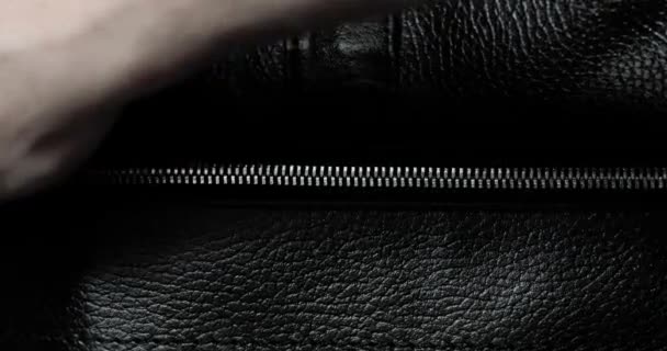 Homme dézips métal zip tester sur un sac noir en cuir, vue rapprochée à la main . — Video