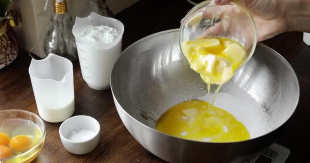 Mulher junta manteiga derretida para tigela de metal e ingredientes de mistura para massa de bolo . — Vídeo de Stock