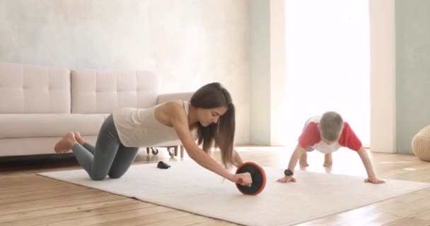 Ibu dan anak membuat latihan olahraga di rumah bersama di karpet di ruang tamu. — Stok Video