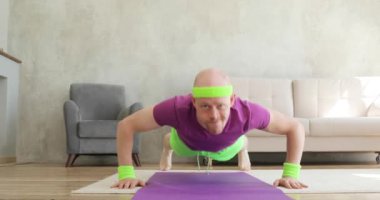 Komik adam minder üzerinde şınav çekip kameraya, fitness esprilerine bakıyor..
