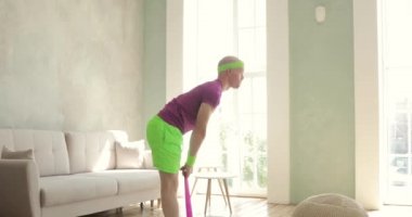 Komik adam evde spor esprisi yapan spor lastiğiyle egzersiz yapıyor..