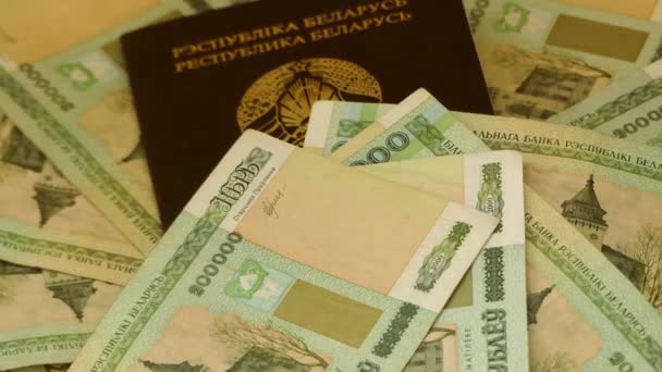Pasaporte de la República de Bielorrusia en cubierta verde con rublos bielorrusos acostados sobre mesa de madera . — Vídeo de stock
