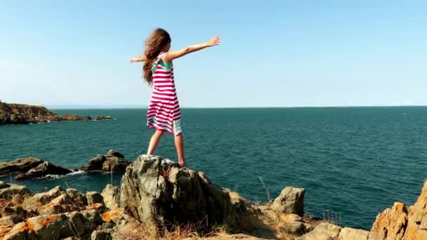 Krásná holčička chodí na kamenné skály na pobřeží Středozemního moře. — Stock video