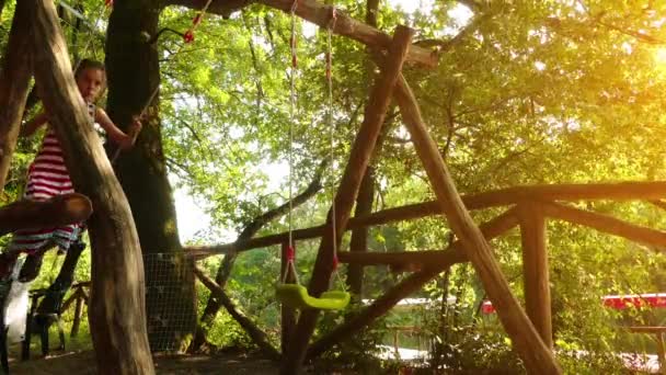 Niña hermosa va a dar un paseo en un columpio en el parque de la ciudad de verano . — Vídeos de Stock